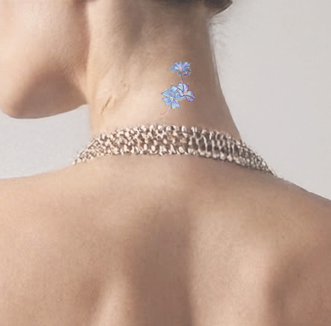 Person wearing a chain necklace with blue floral tattoos on a plain background