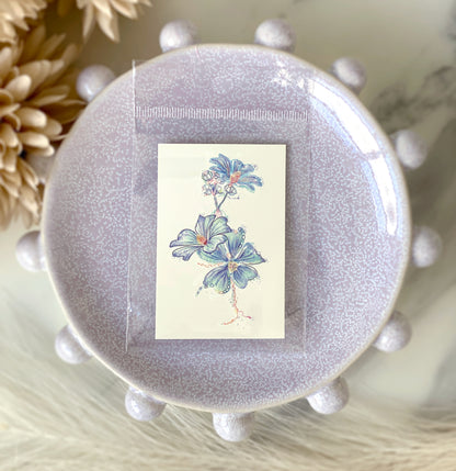 Close-up of three small blue flower temporary tattoos, 2 × 3 inches