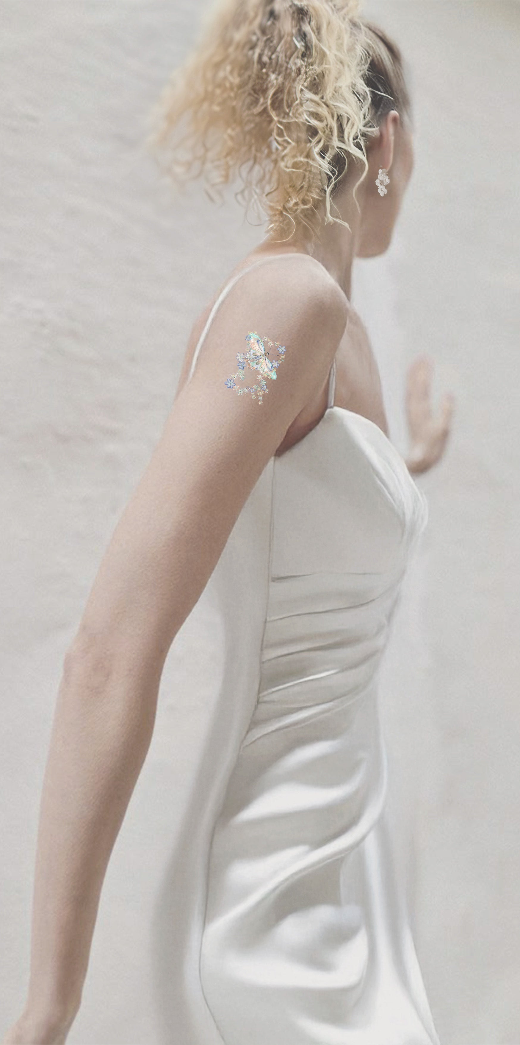 Woman in a white dress with floral arm bandage against a plain background