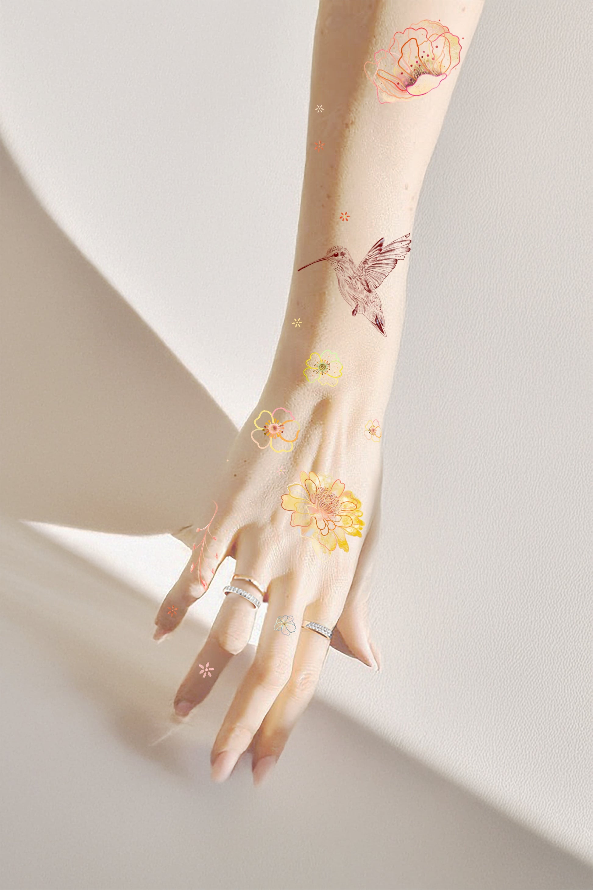 Hand with floral and bird tattoos on a light background