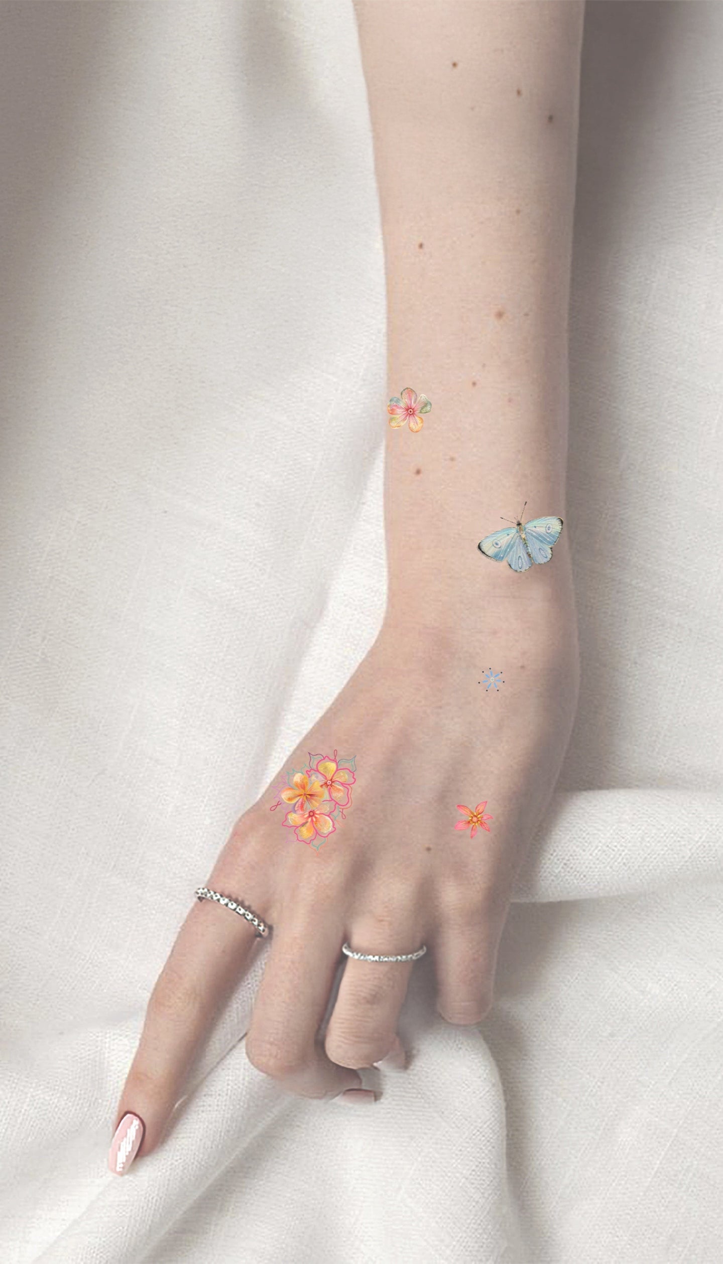 Hand with temporary tattoos of flowers and a butterfly on a white background